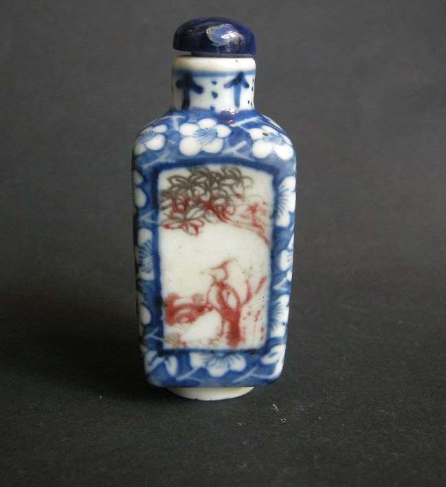 Snuff bottle porcelain quadrangular shape  decorated in underglaze blue with prunus flowers and for panels in copper red  with birds and insects in a landscape